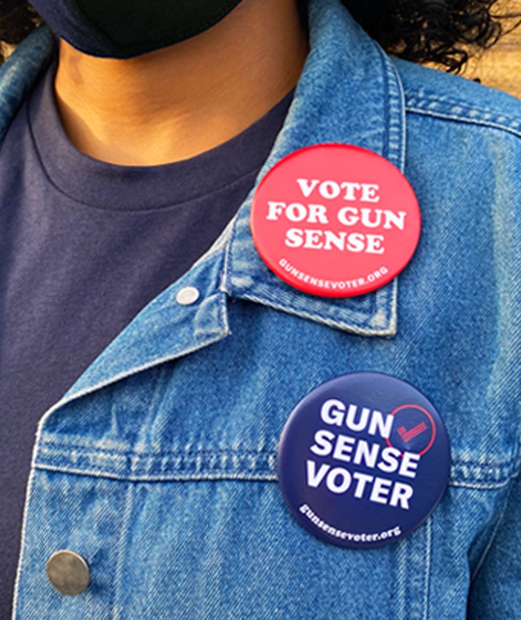 A set of two Gun Sense Voter buttons: one red one that says “Vote for Gun Sense,” the other a navy one that says “Gun Sense Voter”